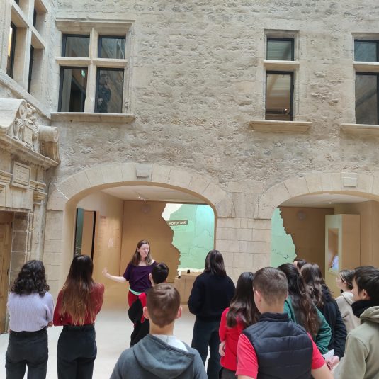 Une guide présente la porte historique du musée à un groupe d'adolescents