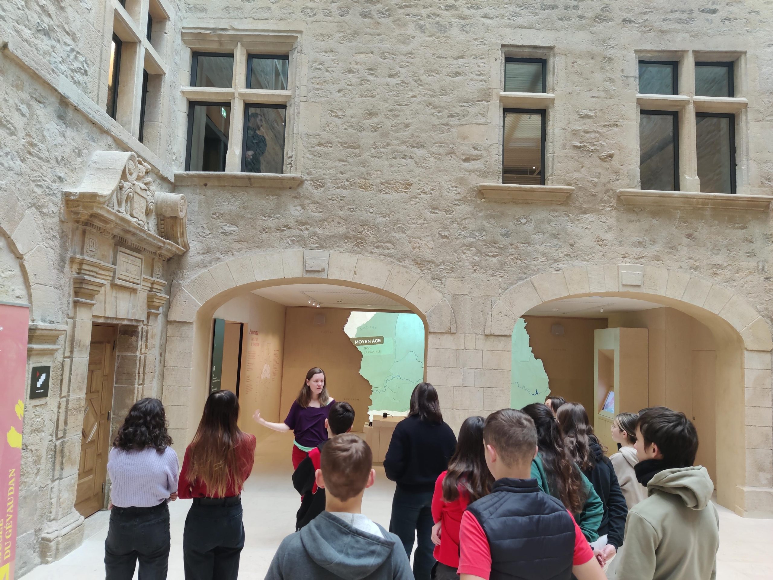 Une guide présente la porte historique du musée à un groupe d'adolescents